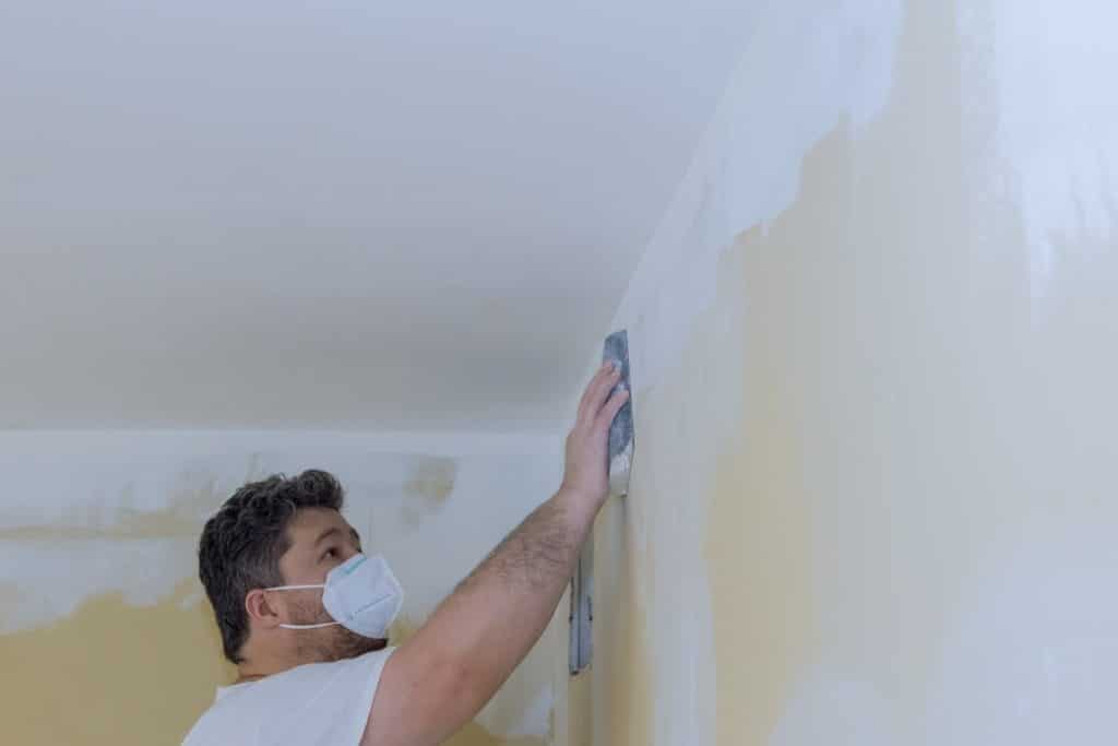 A contractor sanding over a wall